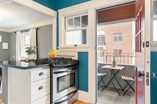 118 NW King Ave Unit 52, Portland, OR 97210 - kitchen with appliances with stainless steel finishes, a sink, dark countertops, white cabinets, and ornamental molding