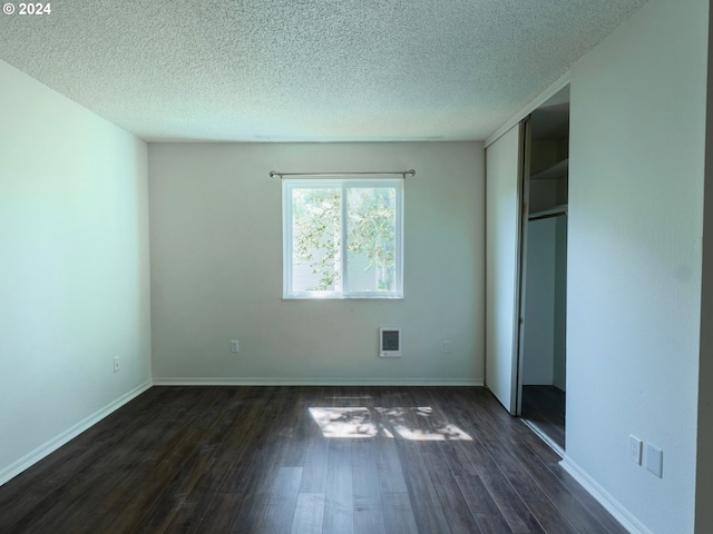 unfurnished room featuring a textured ceiling and dark hardwood / wood-style flooring