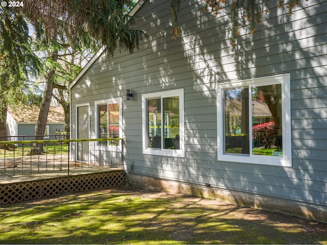 view of property exterior with a deck and a lawn