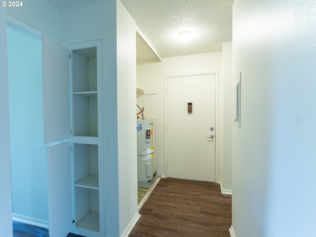 hall featuring a textured ceiling, water heater, dark wood-type flooring, and built in shelves