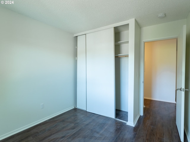 unfurnished bedroom featuring a closet, a textured ceiling, and dark wood-type flooring