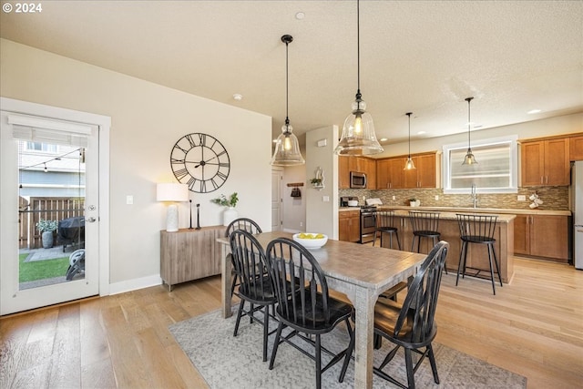 dining room featuring sink, a textured ceiling, and light wood-type flooring