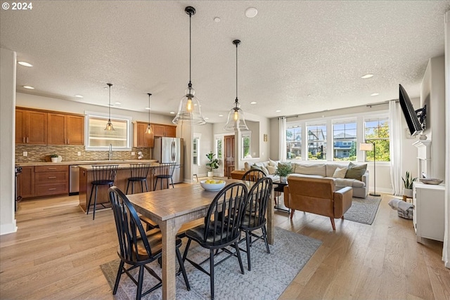 dining room with sink, light hardwood / wood-style floors, and a textured ceiling