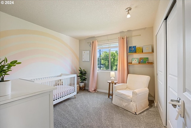 bedroom featuring a nursery area, carpet floors, and a textured ceiling