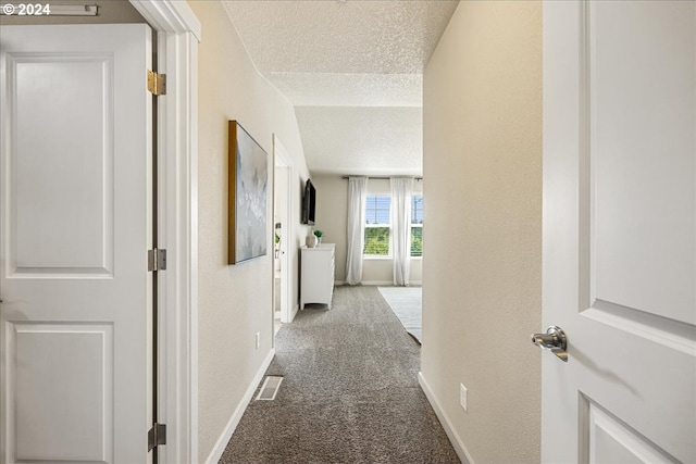 hallway with carpet flooring and a textured ceiling