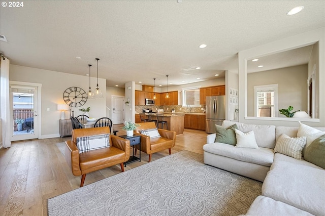 living room with a textured ceiling, a healthy amount of sunlight, and light wood-type flooring