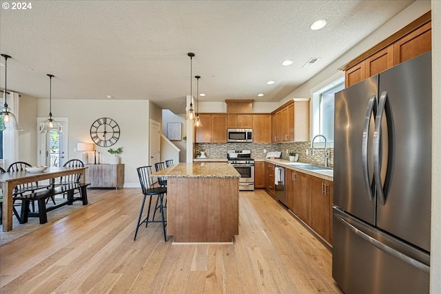 kitchen with stainless steel appliances, hanging light fixtures, a center island, and sink