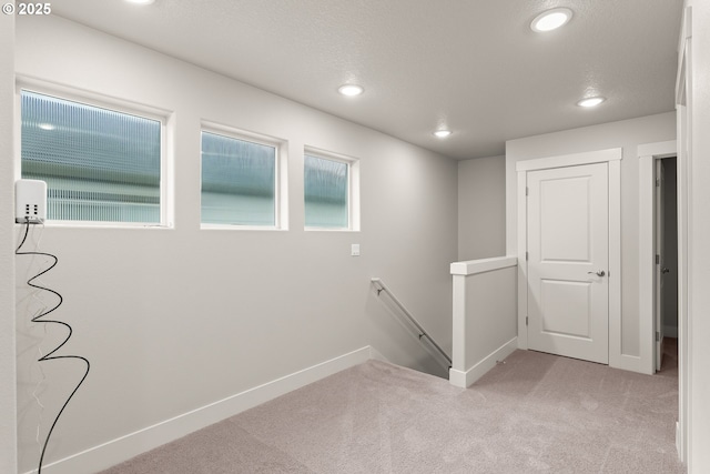 hall with light colored carpet and a textured ceiling