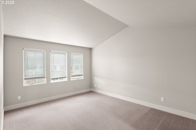 carpeted spare room with vaulted ceiling and a textured ceiling