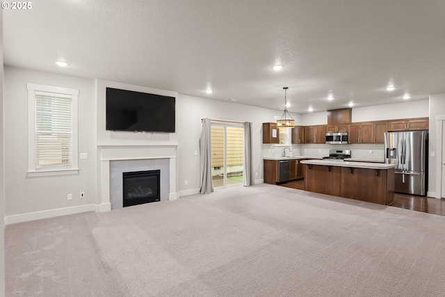 unfurnished living room with a fireplace, sink, and dark carpet