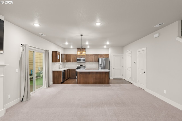 kitchen featuring tasteful backsplash, decorative light fixtures, a center island, carpet floors, and stainless steel appliances