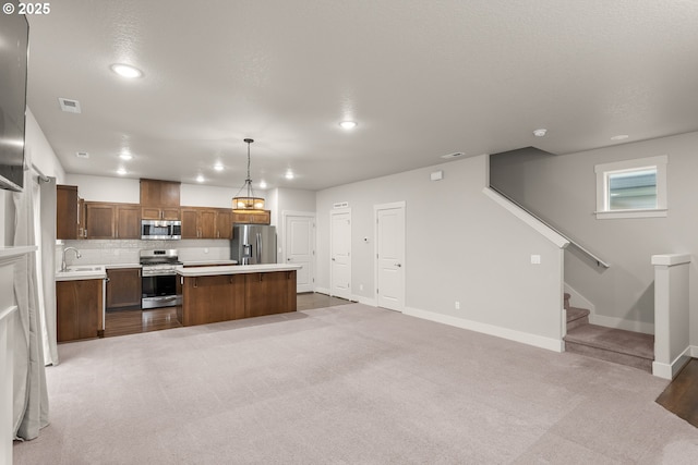 kitchen featuring a kitchen island, appliances with stainless steel finishes, pendant lighting, sink, and decorative backsplash