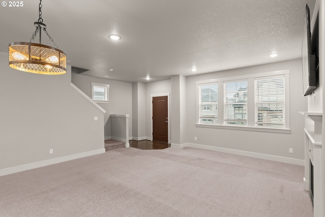 unfurnished living room featuring a healthy amount of sunlight, light colored carpet, and a textured ceiling