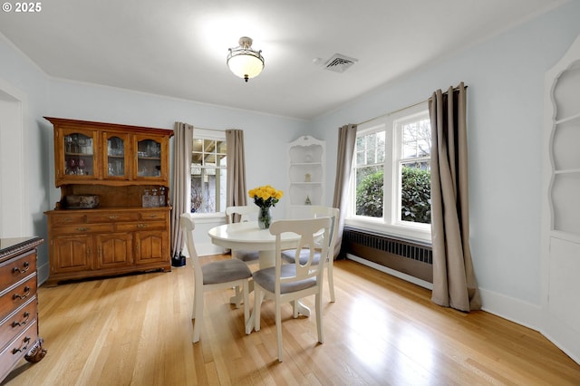 dining area featuring radiator heating unit and light wood-type flooring