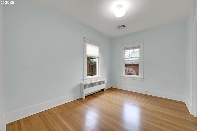 empty room with light hardwood / wood-style floors and radiator