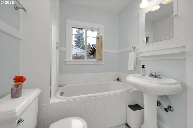 bathroom featuring a relaxing tiled tub and toilet