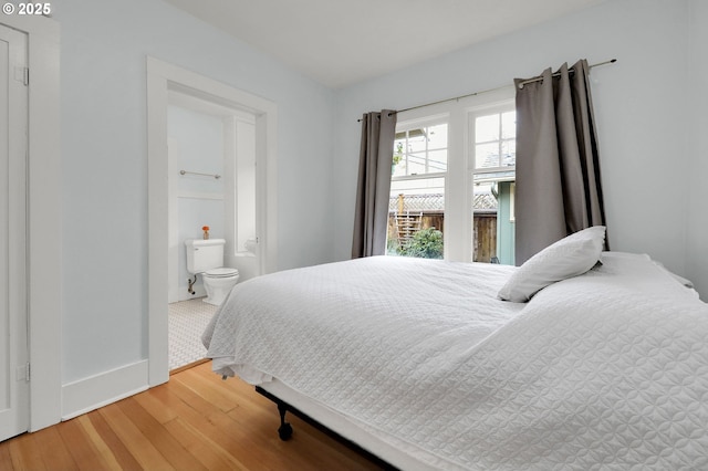 bedroom with ensuite bath and hardwood / wood-style flooring