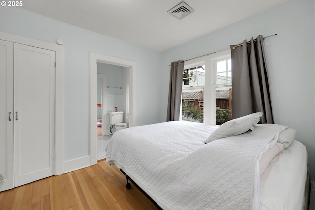 bedroom with ensuite bathroom and hardwood / wood-style flooring