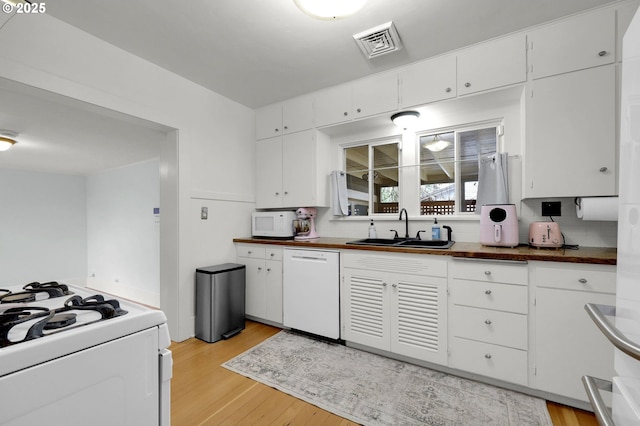 kitchen featuring white cabinetry, sink, backsplash, light hardwood / wood-style floors, and white appliances