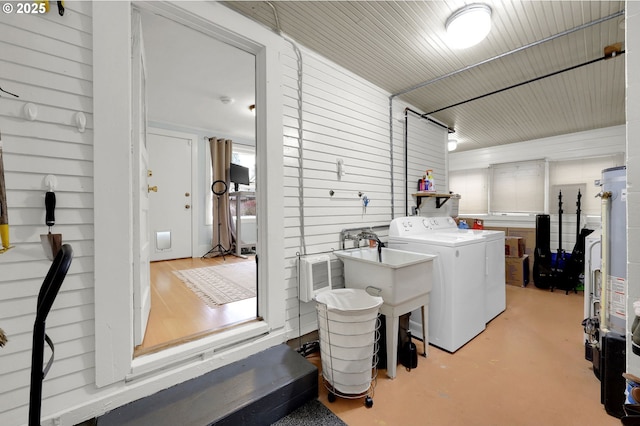 washroom with independent washer and dryer, wooden walls, and sink