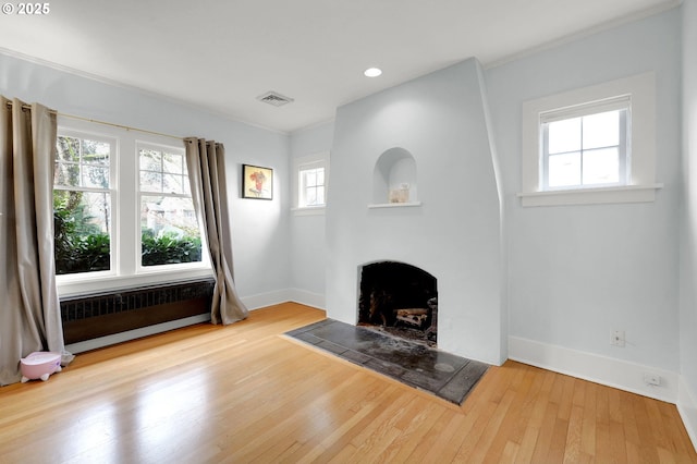 unfurnished living room with a tile fireplace, light hardwood / wood-style floors, plenty of natural light, and crown molding