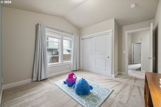 carpeted bedroom featuring a closet, lofted ceiling, and a textured ceiling