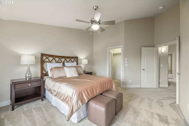 bedroom with light carpet, a spacious closet, a ceiling fan, and baseboards