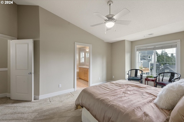 bedroom featuring vaulted ceiling, light colored carpet, ceiling fan, connected bathroom, and a textured ceiling