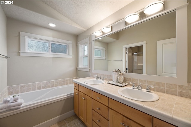 full bathroom featuring double vanity, a textured ceiling, vaulted ceiling, and a sink