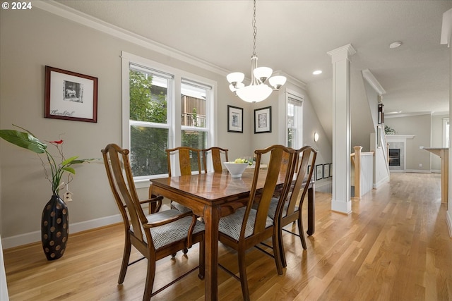 dining space with ornamental molding, light wood-type flooring, a chandelier, and decorative columns