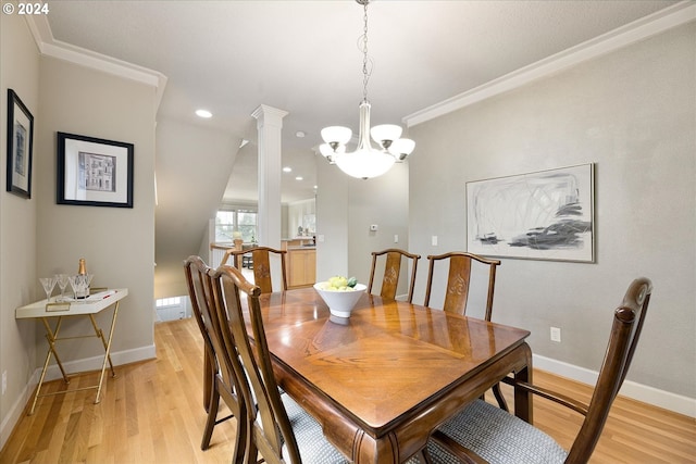 dining room with ornamental molding, an inviting chandelier, decorative columns, and light hardwood / wood-style floors