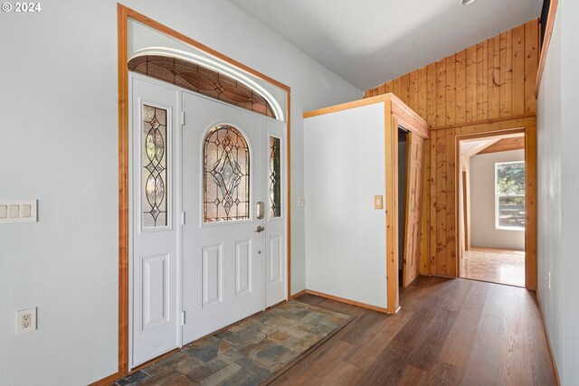 entrance foyer with dark wood-type flooring and wood walls