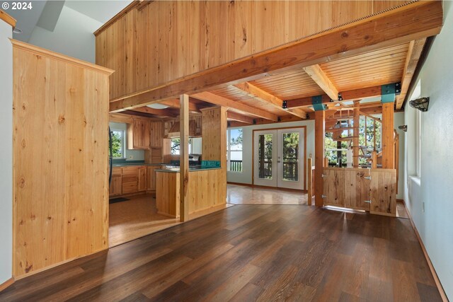 unfurnished living room featuring wooden walls, french doors, wooden ceiling, dark hardwood / wood-style floors, and beam ceiling