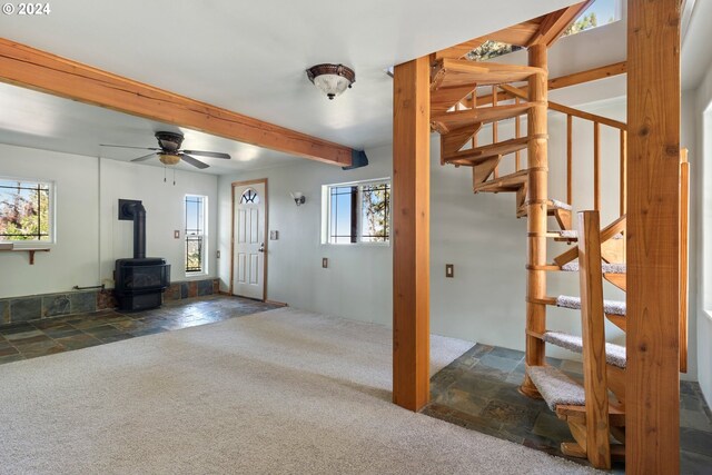 interior space featuring a healthy amount of sunlight, ceiling fan, and a wood stove