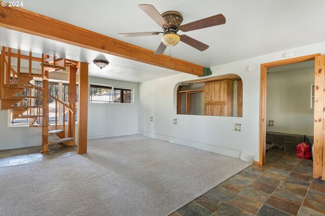 unfurnished living room with ceiling fan and dark colored carpet