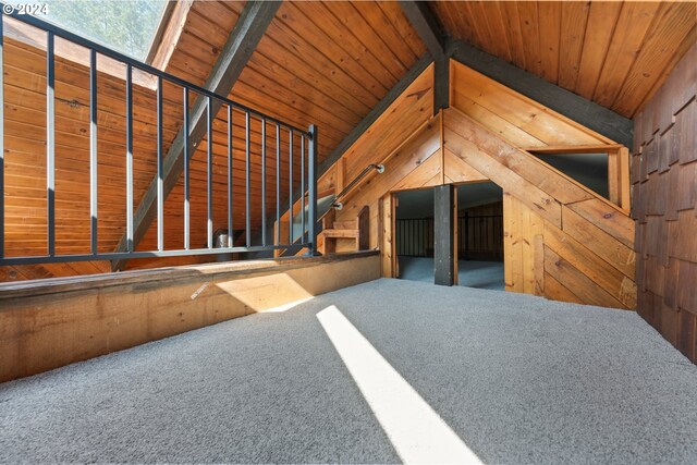 unfurnished living room featuring carpet, wooden walls, wooden ceiling, and lofted ceiling with beams