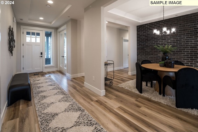 entryway with brick wall, a raised ceiling, and hardwood / wood-style flooring