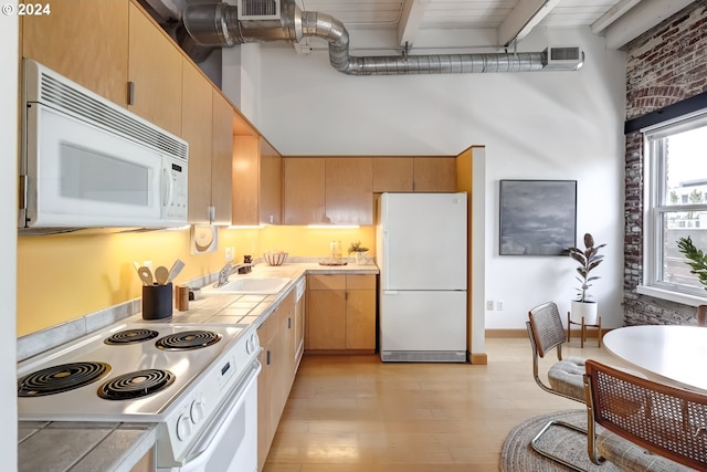 kitchen featuring tile counters, light wood-type flooring, white appliances, and beam ceiling