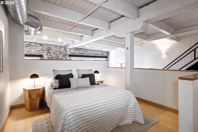 bedroom featuring light wood-type flooring, multiple windows, and beam ceiling