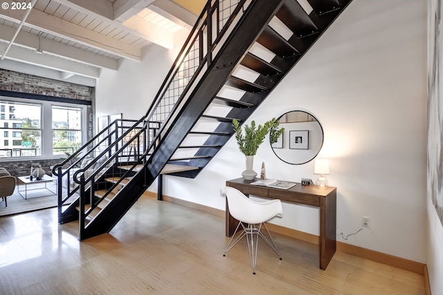 stairs featuring beamed ceiling and hardwood / wood-style flooring