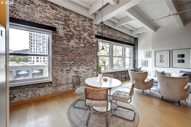 dining space with wooden ceiling, beamed ceiling, light hardwood / wood-style flooring, and brick wall