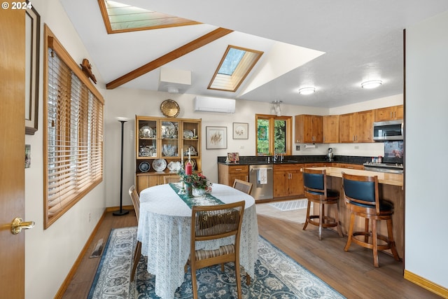 dining room featuring sink, vaulted ceiling with skylight, light hardwood / wood-style floors, and an AC wall unit