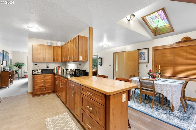 kitchen with a skylight, a textured ceiling, and kitchen peninsula