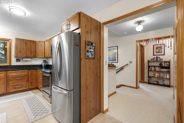 kitchen with light carpet, stainless steel appliances, and a textured ceiling