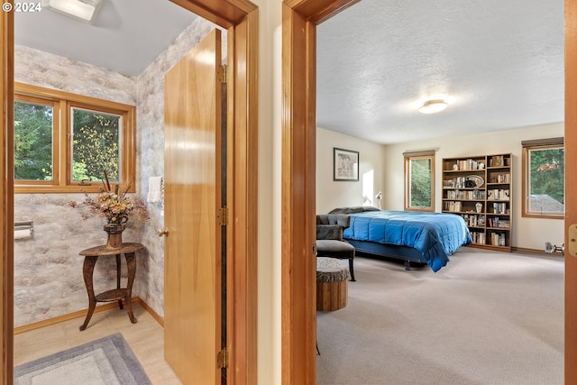 bedroom with light carpet, a textured ceiling, and a baseboard heating unit