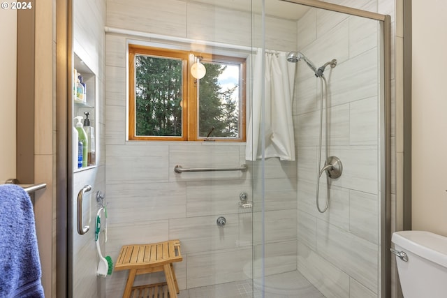 bathroom featuring toilet and a shower with shower door