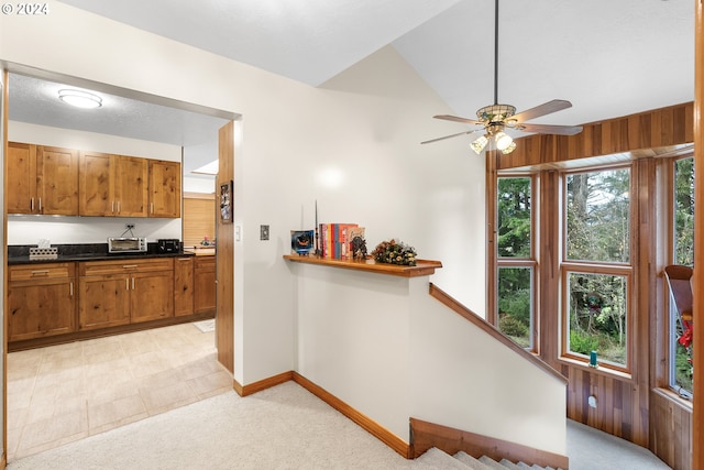 kitchen with light carpet, ceiling fan, and wood walls