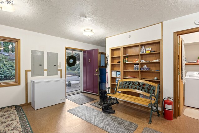 entrance foyer with washer / clothes dryer, electric panel, and a textured ceiling