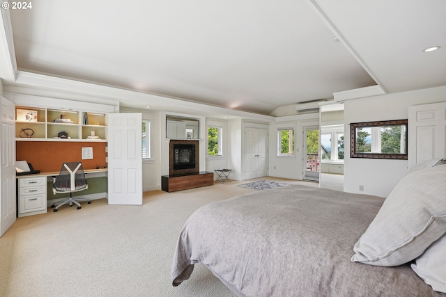 bedroom featuring built in desk, light carpet, and an AC wall unit