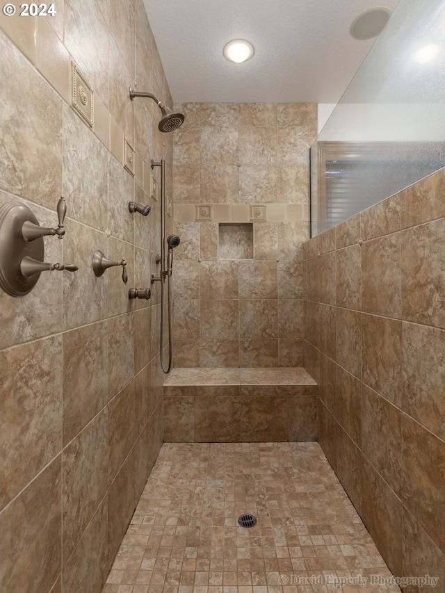 bathroom featuring a textured ceiling and a tile shower